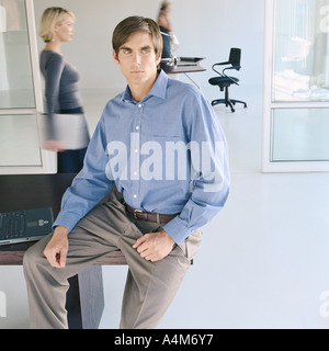 Homme assis sur le bord du bureau en bureau actif Banque D'Images