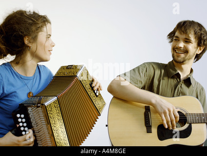 Jeune homme jouant de la guitare, jeune femme jouant de l'accordéon Banque D'Images