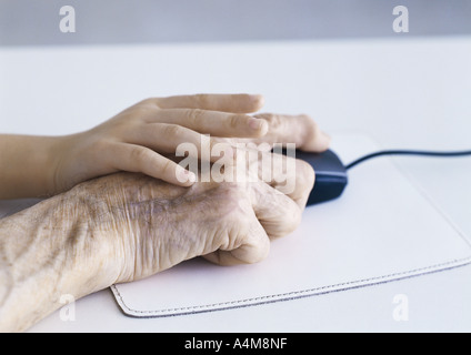 La main de l'enfant et des personnes âgées la main de l'homme sur la souris d'ordinateur Banque D'Images