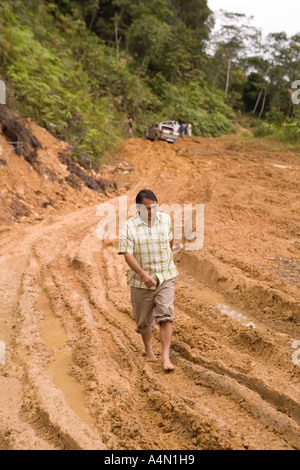 Malaisie Bornéo Sarawak Belaga homme marchant du mode 4 roues motrices véhicule bloqué sur la piste d'exploitation forestière boueux Banque D'Images