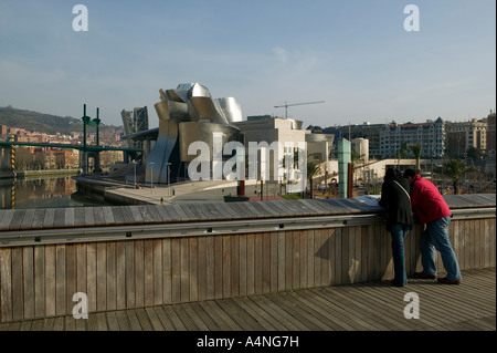 Deux personnes lisant sur Puente pont Pedro Arrupe, Musée Guggenheim de Bilbao, l'arrière-plan, Pais Vasco / Pays Basque Banque D'Images