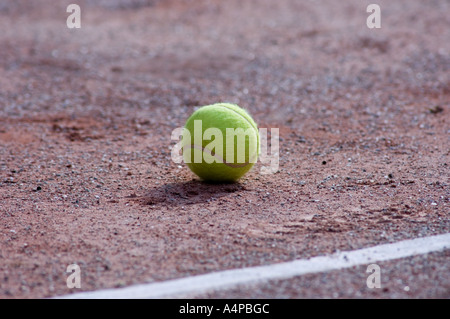 Balle de tennis sur une surface de gravier avec une ligne blanche Banque D'Images