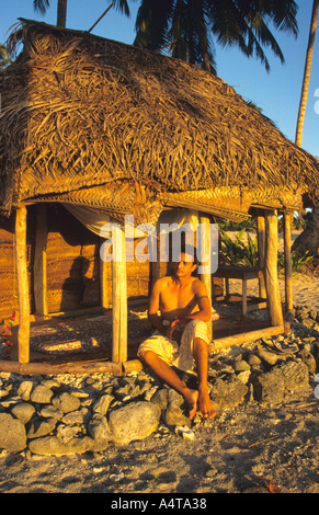 Jeune homme Samoan de l'Ouest jouit d'un coucher du soleil doré dans sa chambre ,FALE sans murs, qui est l'habitation typique des îles Banque D'Images