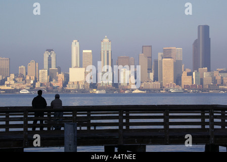 Un couple se tient le long d'un quai situé à West Seattle comme l'horizon de la ville est perçu à travers le Puget Sound Banque D'Images
