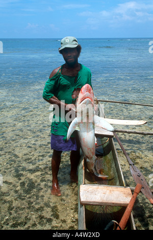 Un requin appelant de Kontu village sur la côte ouest de l'Irlande nouvelle apporte dans un requin qu'il a capturé Banque D'Images