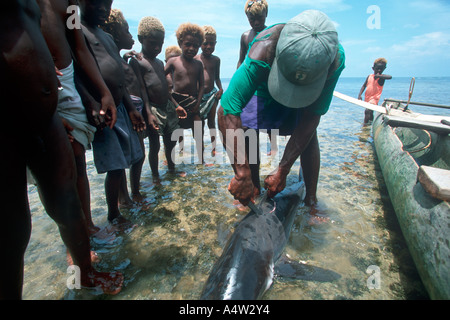 Un requin Obet appelant de Kontu village est entouré d'enfants excités après avoir présenté un requin qu'il a capturé Banque D'Images