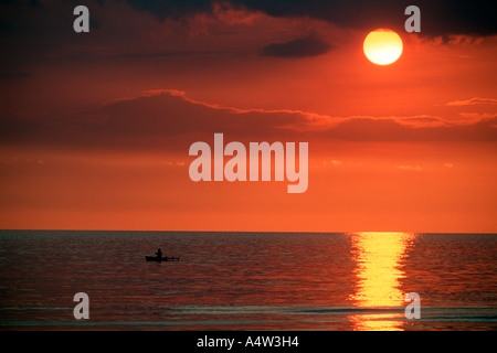 Robert un requin appelant de Kontu paddles jusqu'à la limite du récif au coucher du soleil pour faire des incantations de lui apporter chance dans sa hun Banque D'Images