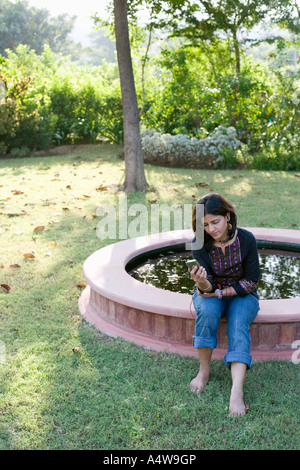 Woman listening to mp3 player en bordure de fontaine Banque D'Images