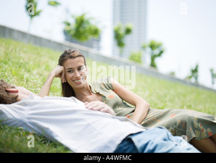 Jeune couple lying on grass in urban park Banque D'Images