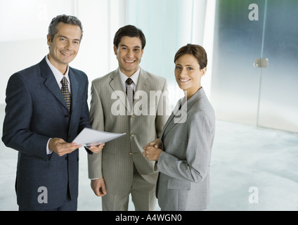 Trois des associés d'affaires debout dans hall, smiling Banque D'Images