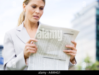 Businesswoman reading financial pages de journal Banque D'Images