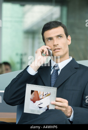 Man talking on phone et calendrier de portefeuille Banque D'Images