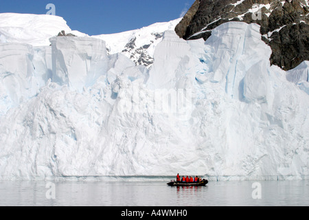 Groupe de voyageurs de l'Antarctique sur un canot zodiac croisière autour de hautes falaises de glace Banque D'Images