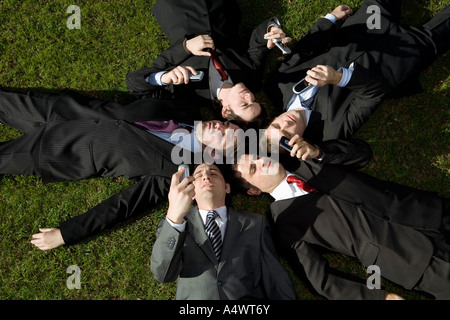 Hommes d'utiliser leurs téléphones cellulaires pose dans l'herbe Banque D'Images