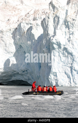 Des passagers à bord d'un zodiac cruising devant un grand mur de glace de la péninsule antarctique,. Banque D'Images