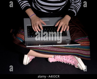 Jeune fille en vêtements boho avec pompes rose on laptop computer Banque D'Images