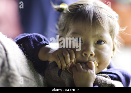 CAPELLANILLA GUATEMALA jeune Maya Quiché enfant de manger des bonbons comme elle est effectuée dans une écharpe Banque D'Images