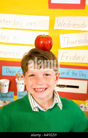 Garçon avec apple on head in classroom Banque D'Images