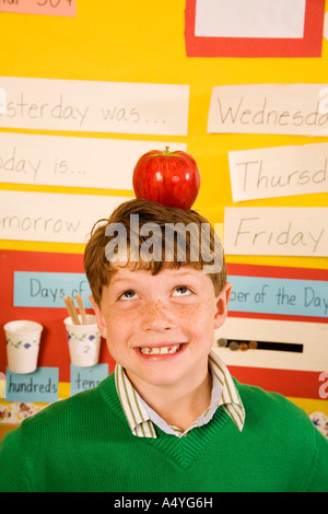 Garçon avec apple on head in classroom Banque D'Images