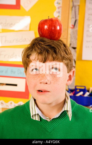 Garçon avec apple on head in classroom Banque D'Images