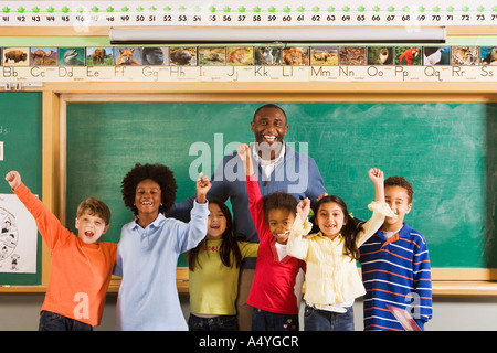 Enseignant et élèves cheering in classroom Banque D'Images