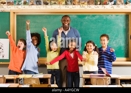 Enseignant et élèves cheering in classroom Banque D'Images