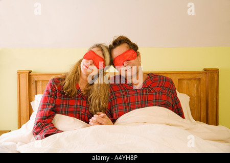 Couple sitting in bed portant des masques de l'œil Banque D'Images