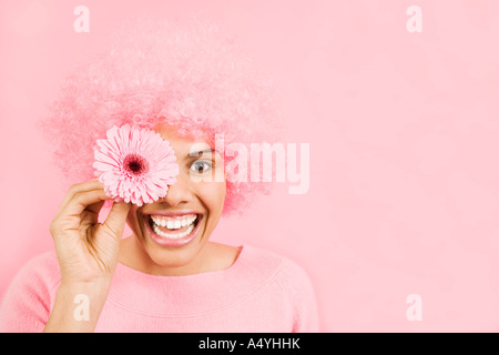 Femme portant une perruque rose et des yeux plus holding flower Banque D'Images