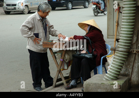 Vieille Femme vendant des billets de loterie sur coin de rue Hanoi Vietnam Asie du sud-est Banque D'Images