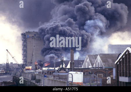 Woolwich les flammes et la fumée s'élevant au-dessus de la Tamise à côté du feu d'entrepôt à marée basse Banque D'Images