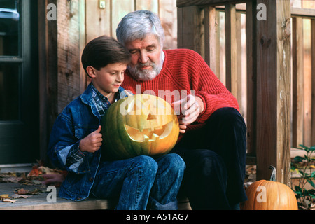 Grand-père et petit-fils d'inspecter la citrouille sculptée sur le porche Banque D'Images