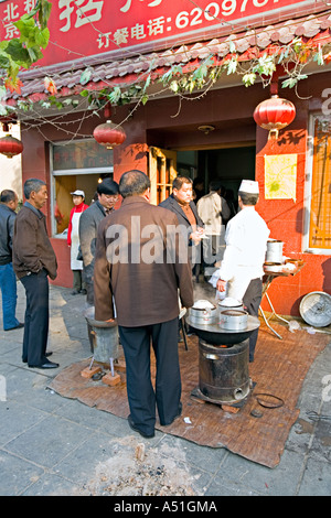 Chine Pékin petit mais occupé restaurant du quartier avec des chefs mis en place sur le trottoir pour préparer le petit déjeuner quenelles Banque D'Images