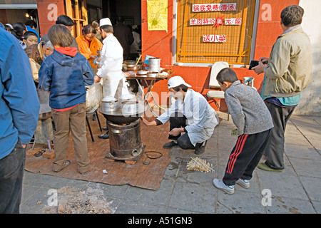 Chine Pékin petit mais occupé restaurant du quartier avec des chefs mis en place sur le trottoir pour préparer le petit déjeuner quenelles Banque D'Images