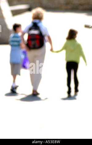 La famille le jour de l'été à l'école à pied tenant la main et crossing road et être en bonne santé en n'utilisant pas une voiture à Londres UK Banque D'Images