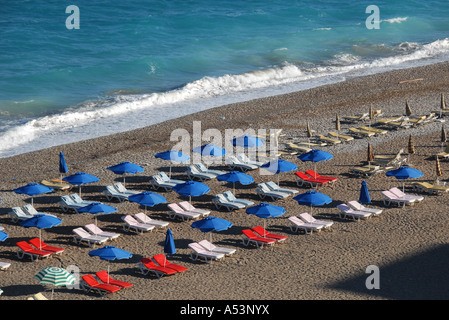 Chaises longues et parasols sur une plage de la ville de Rhodes, Grèce tôt le matin avant que les gens arrivent Banque D'Images