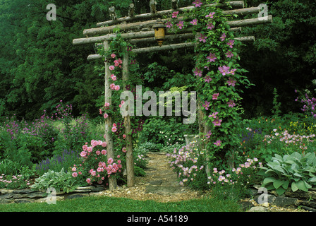 Cèdre rustique arbor avec roses et clématites sert d'entrée de la partie ombrée du jardin de fleurs, Missouri USA Banque D'Images