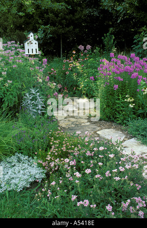 En chemin en dalles de jardin avec cabane d'église unique ou birdbox avec violet pastel fleurs, Midwest USA Banque D'Images