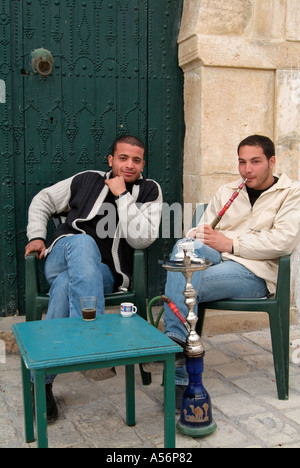 Les jeunes hommes fumant la pipe Shisha, café par la mosquée, Place Bou Makhlouf, Le Kef, Tunisie Banque D'Images