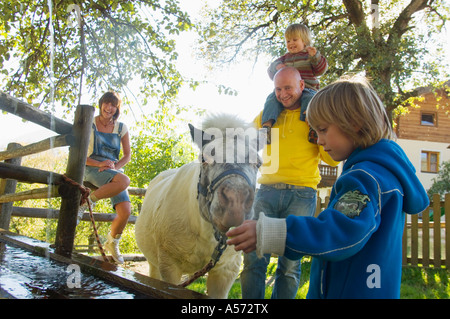 Family watching pony à Fontaine, homme portant sur l'épaule du garçon Banque D'Images