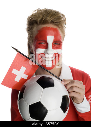 Jeune homme avec drapeau suisse peint sur le visage et le holding football et d'un drapeau Banque D'Images