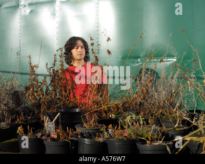 Jeune homme en rouge l'article parmi les plantes mortes en pots Banque D'Images