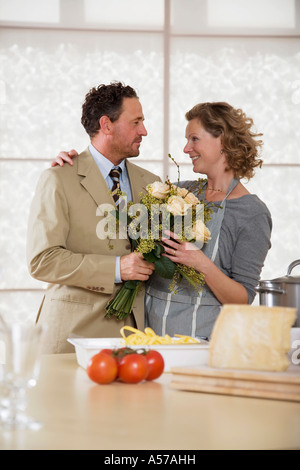 D'âge mûr en cuisine avec bouquet de fleurs Banque D'Images