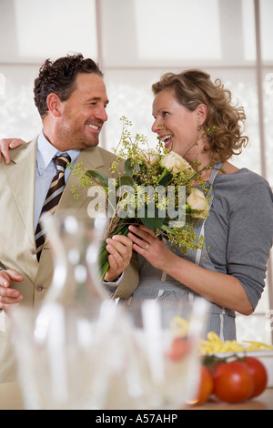 D'âge mûr en cuisine avec bouquet de fleurs Banque D'Images