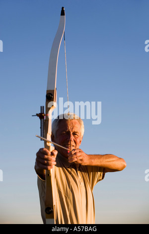 Senior adult man à l'aide d'arc et flèche Banque D'Images