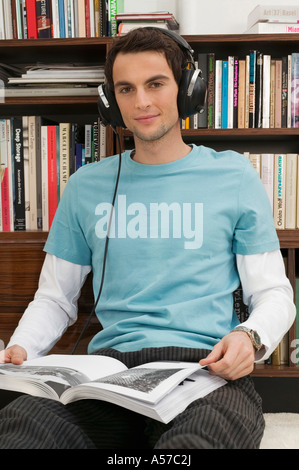 Jeune homme assis sur le sol, portant des écouteurs Banque D'Images