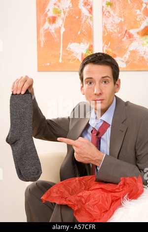 Man sitting on sofa holding, chaussettes, portrait Banque D'Images