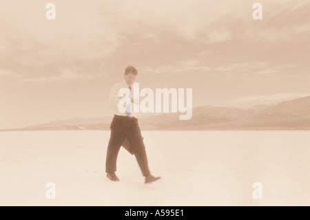 Businessman checking sa montre bien que de marcher à travers un paysage désertique aride Banque D'Images
