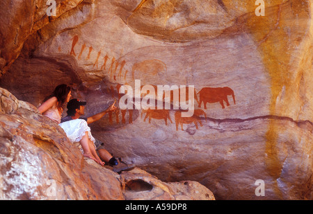 Couple admiring San peintures dans le complexe de grottes, Stadhall Cederberg, Wilderness, Afrique du Sud Banque D'Images