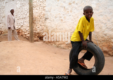 Harar, Éthiopie, petit garçon sur un pneu vieil homme dans l'arrière-plan dans les petites rues à l'intérieur des murs de Harar Banque D'Images