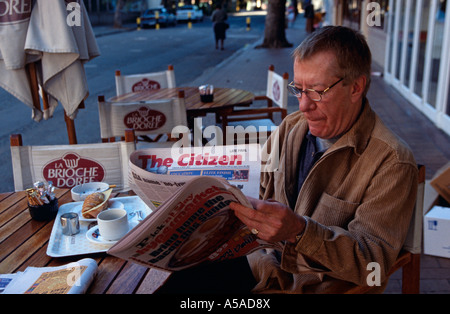 Un homme lit le journal dans un café à Johannesburg Banque D'Images